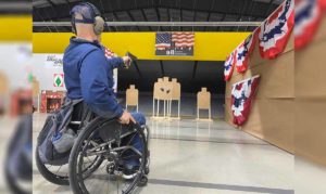 A disabled person shoots a pistol at IDPA-style targets from a wheelchair during the Adaptive Defense Shooting Summit (ADSS)