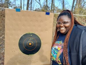 A young black female poses with her target during a free First Shots firearm course at Martin County Firearms Academy in Williamston, N.C.