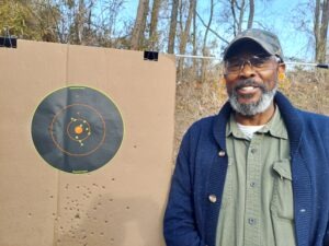 A middle-aged black male poses with his target during a free First Shots firearm course at Martin County Firearms Academy in Williamston, N.C.