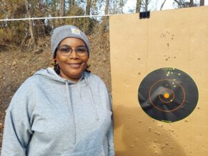 A middle-aged black female poses with her target during a free First Shots firearm course at Martin County Firearms Academy in Williamston, N.C.
